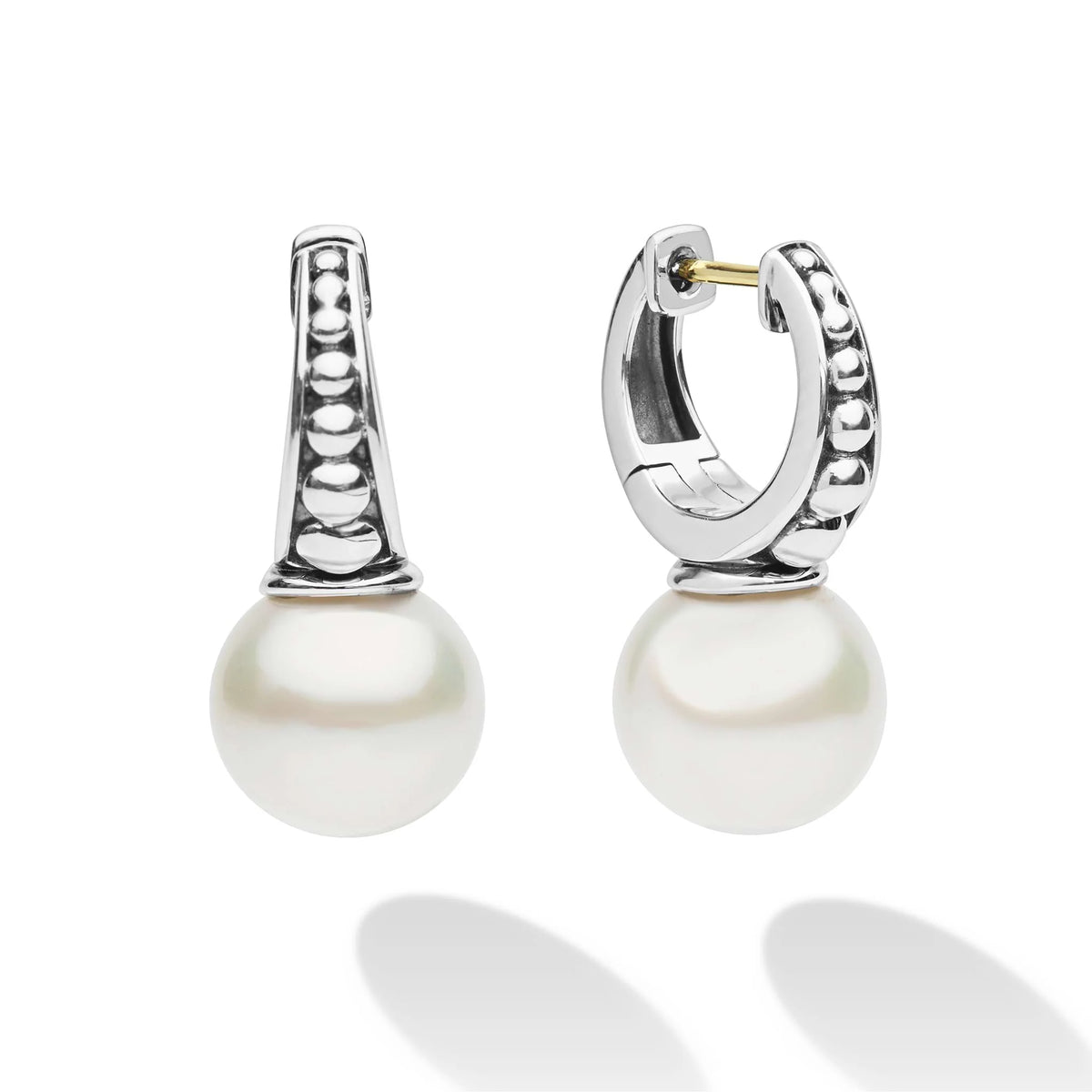 A pair of silver huggie hoop earrings with a vertical bar set with small round stones and a large white pearl drop, shown on a white background with soft reflections.
