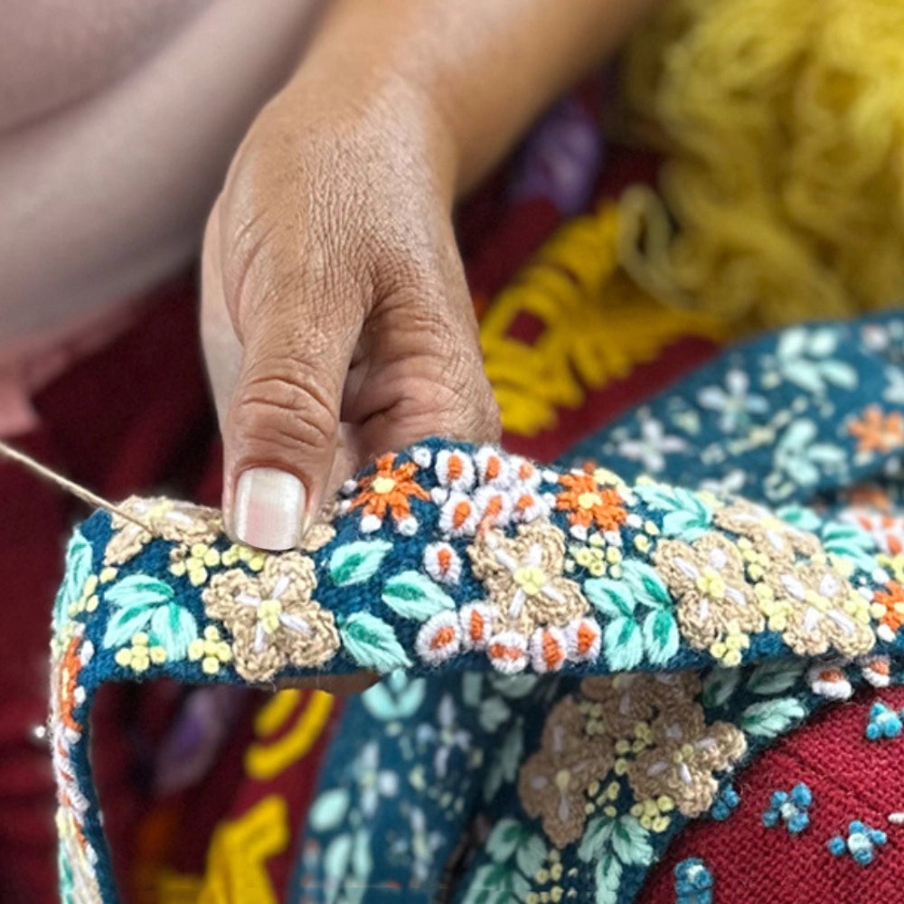 Person sowing floral pattern wool belt with other belts.