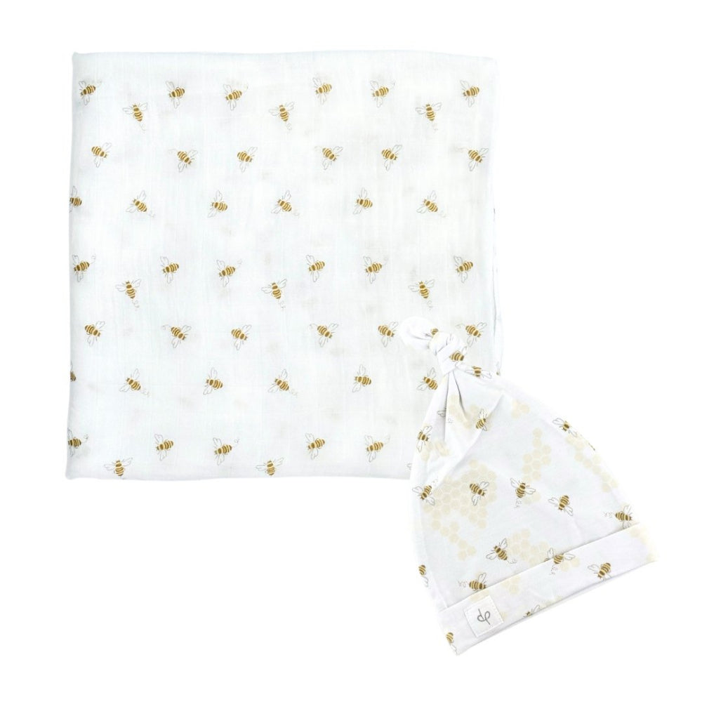 A white bamboo muslin swaddle blanket with a pattern of bees and a matching topknot cap.