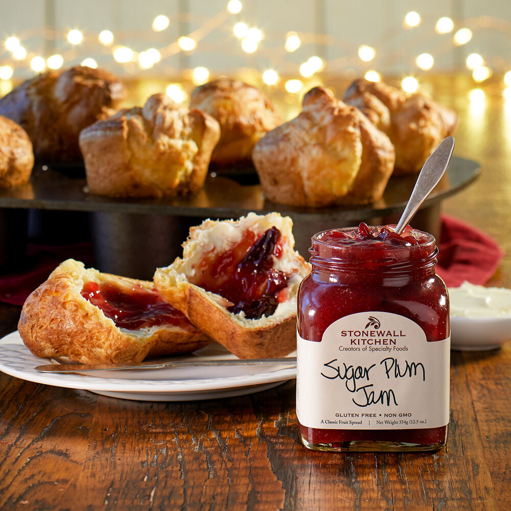 Jar of Stonewall Kitchen Sugar Plum Jam on a wooden table with pastries in the background.