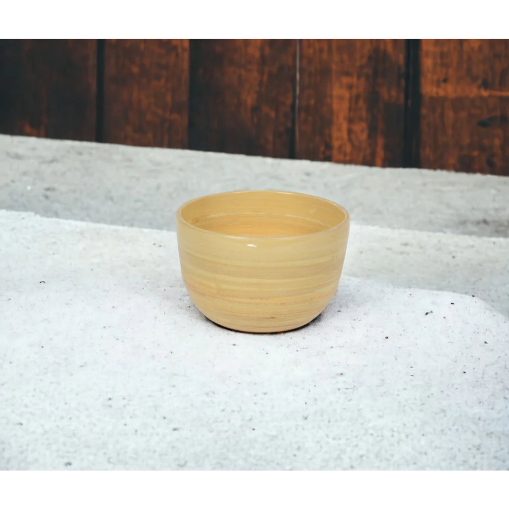 Beige bamboo bowl on a textured surface with a wooden background