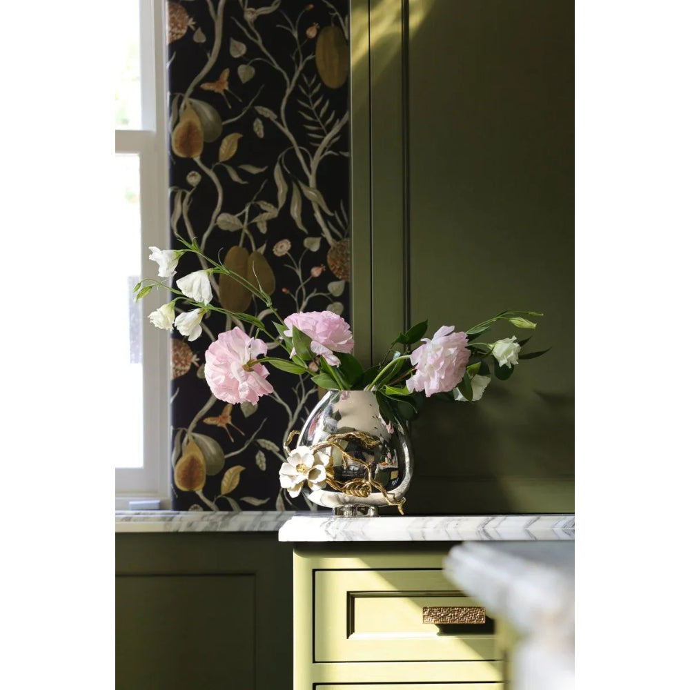 Decorative vase with pink flowers on a marble surface next to a cabinet with floral wallpaper.