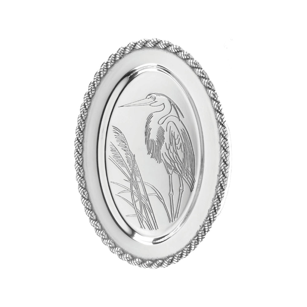 A silver alumium oval platter with an engraved design of a heron and reeds on a white background
