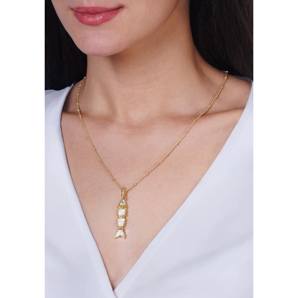 A gold chain necklace with a vertical pendant featuring white stones, shown worn on a model's neck over a white V-neck top.