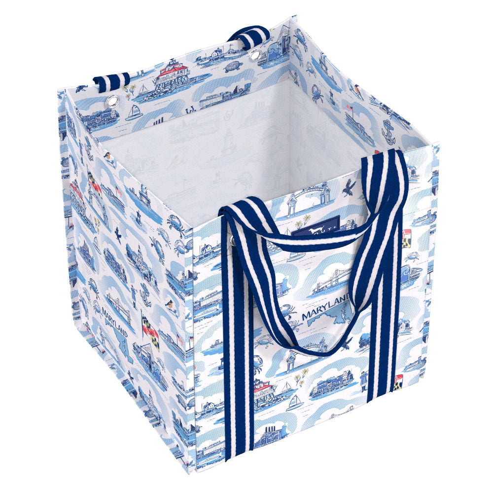 A square fabric storage bin with a nautical-themed print featuring ships, boats, and waves in blue and white. It has thick navy blue and white striped handles and is shown on a clean white background.