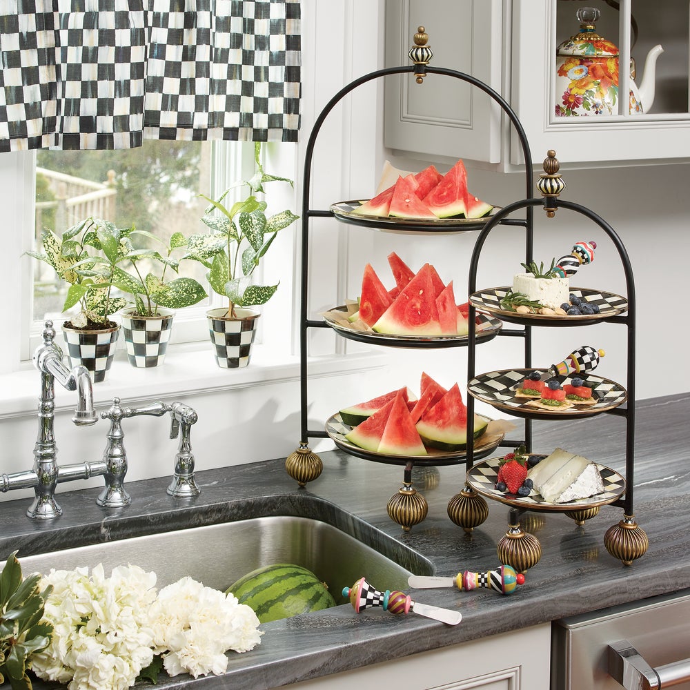 Three-tiered decorative stand with watermelon slices and other items on a kitchen counter.