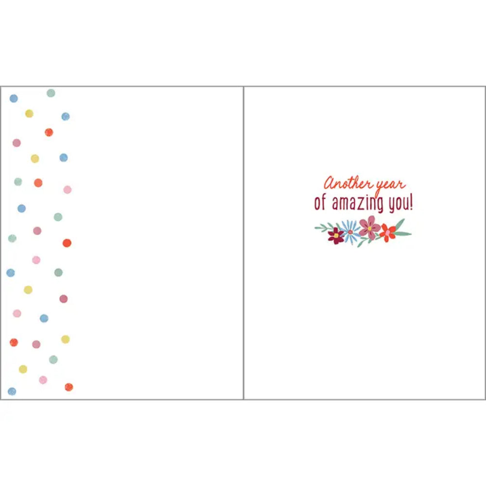 An open greeting card with a white interior. The left panel has a vertical column of small multicolored confetti dots along the left edge.