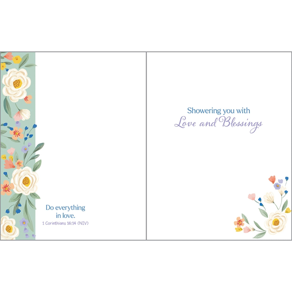 A square floral shower card design with a white center panel, blue text reading 'Showering you with Love and Blessings,' a small Bible verse in the lower left, and watercolor-style flowers along the left and lower right edges.