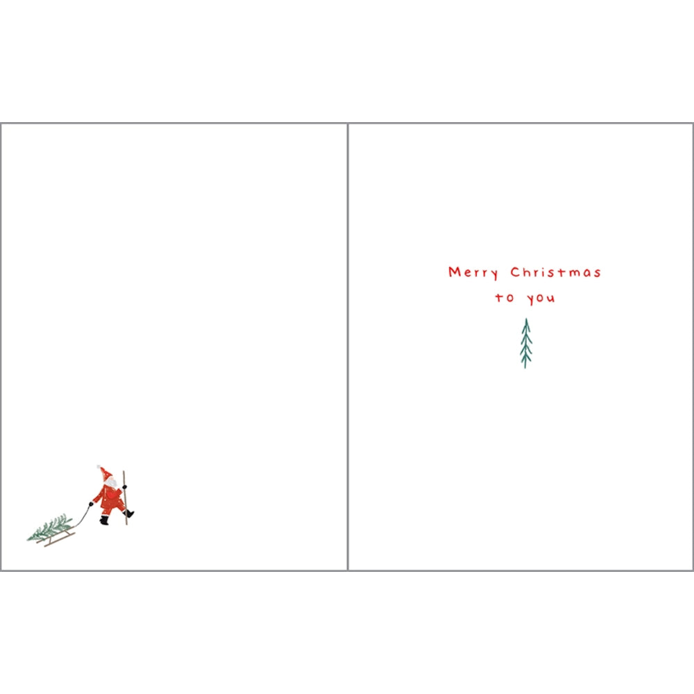 A minimalist Christmas greeting card shown open, with a white front and back. The left side features a small red figure carrying a green Christmas tree, and the right side has red text reading 'Merry Christmas to you' above a small green tree.