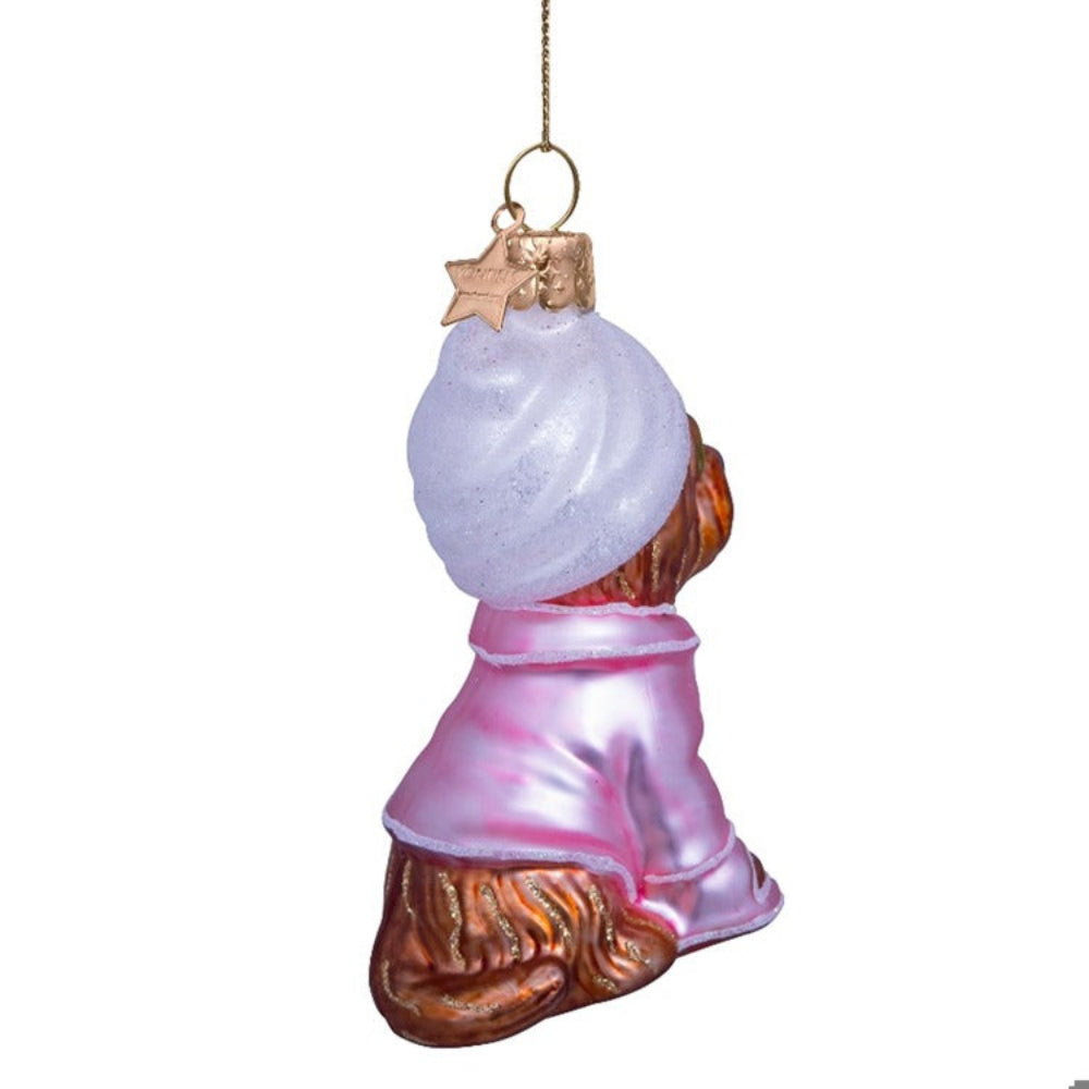 Glass ornament of a dog with a snowball on a white background