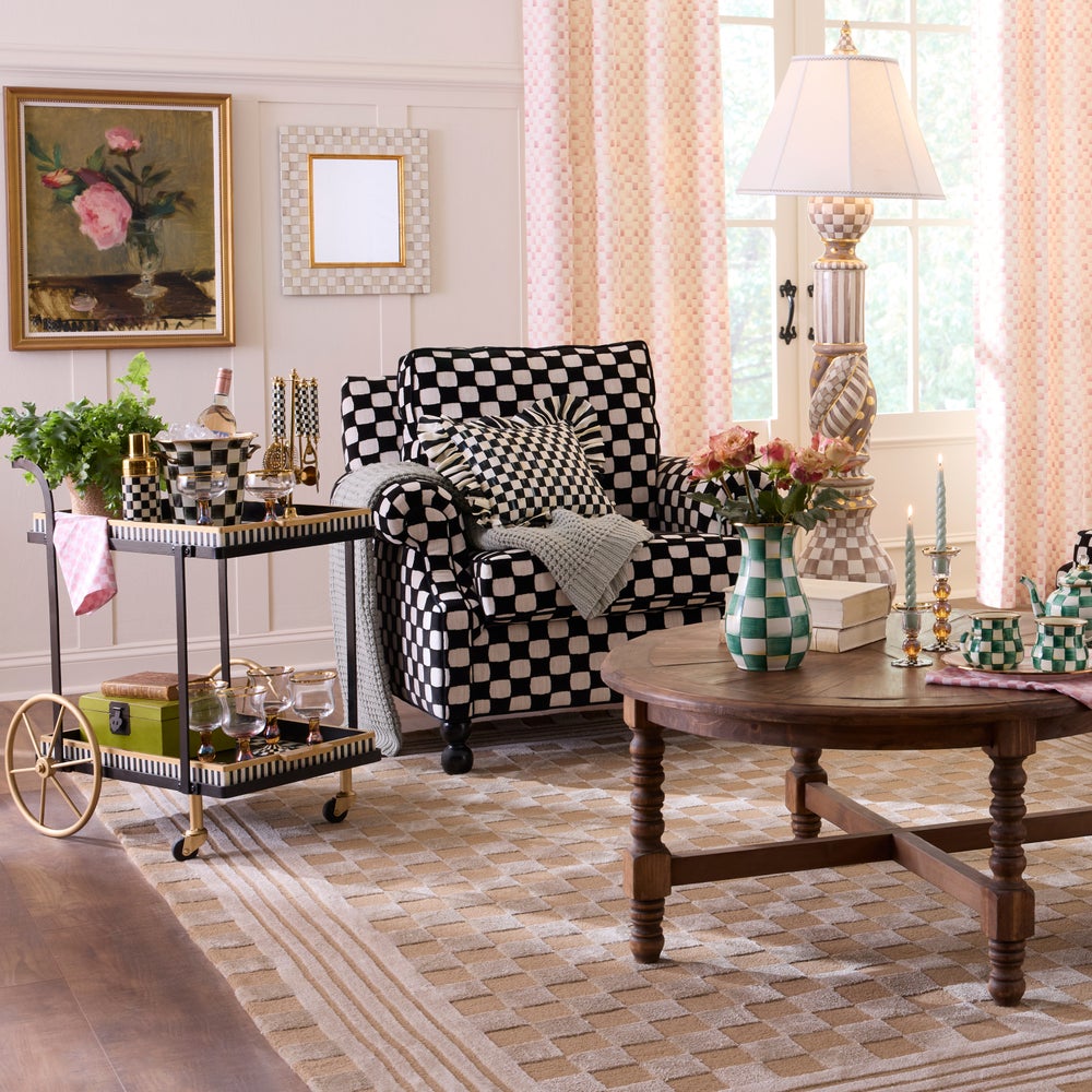 Living room with checkered armchair, wooden table, and decorative items.