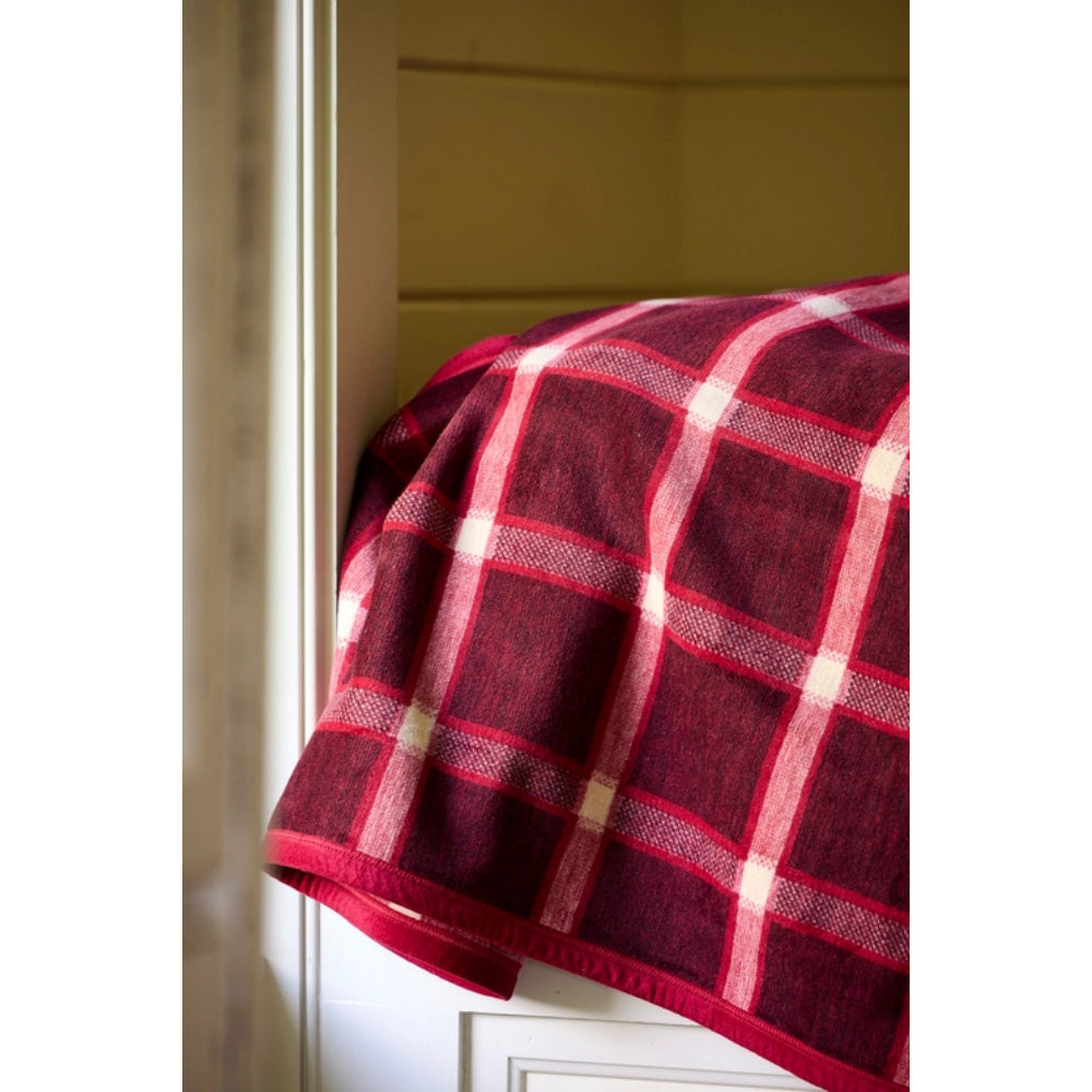 A close-up of a red and white plaid blanket draped over the corner of a white cabinet in a home interior.