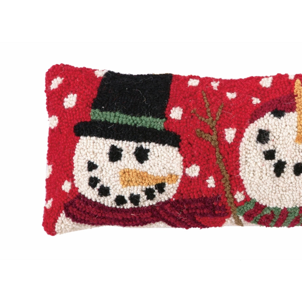 A close-up of a red and white textured rug featuring snowman faces, with one full snowman wearing a black hat and scarf and another partially visible on the right.