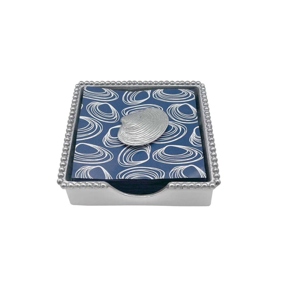 Silver clam shell on a blue and white patterned napkin in a box