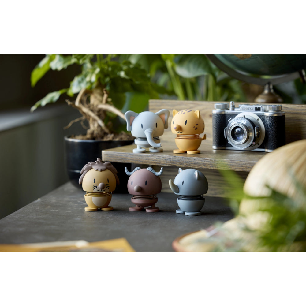 Set of small animal figurines on a wooden stand with a vintage camera in the background.