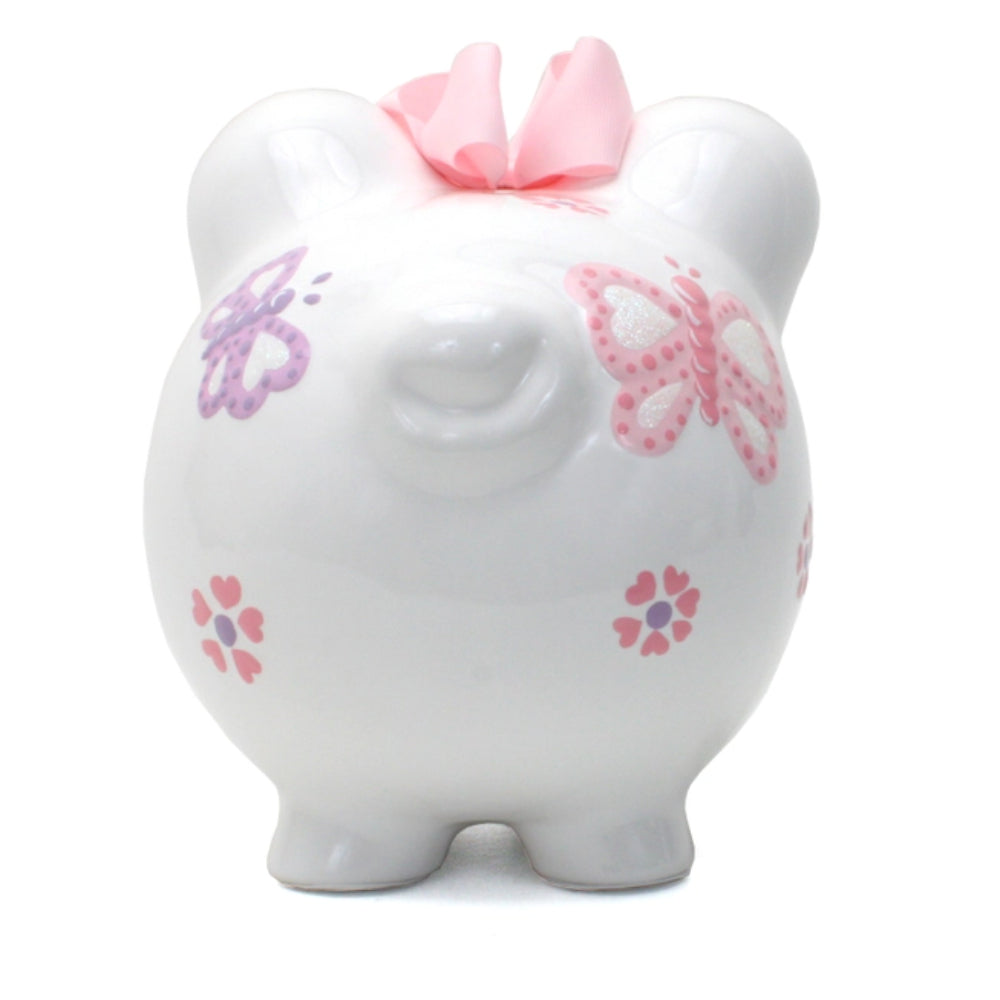 A white ceramic piggy bank with pink and purple butterfly decorations, pink ears, and a pink bow on top.
