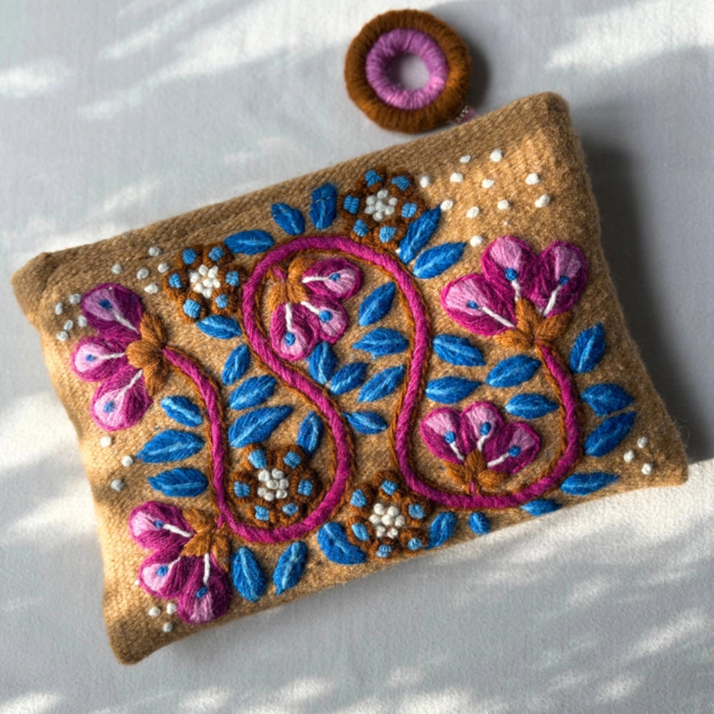 Decorative pouch with floral embroidery on a white surface