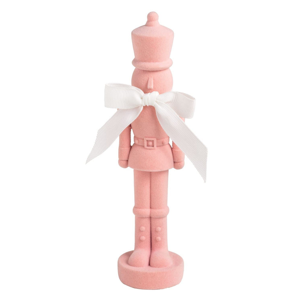 Pink nutcracker figurine with a white bow on a white background.