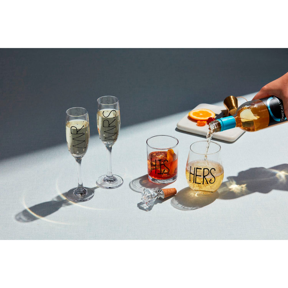 Two champagne flutes labeled 'HIS' and 'HERS' with a bottle being poured into a glass.