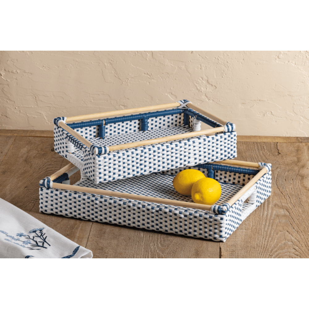 Two woven storage baskets with a blue and white polka dot pattern and light wood frames, stacked on a wooden floor against a beige wall. One basket is open and contains two yellow lemons, while the other is closed.