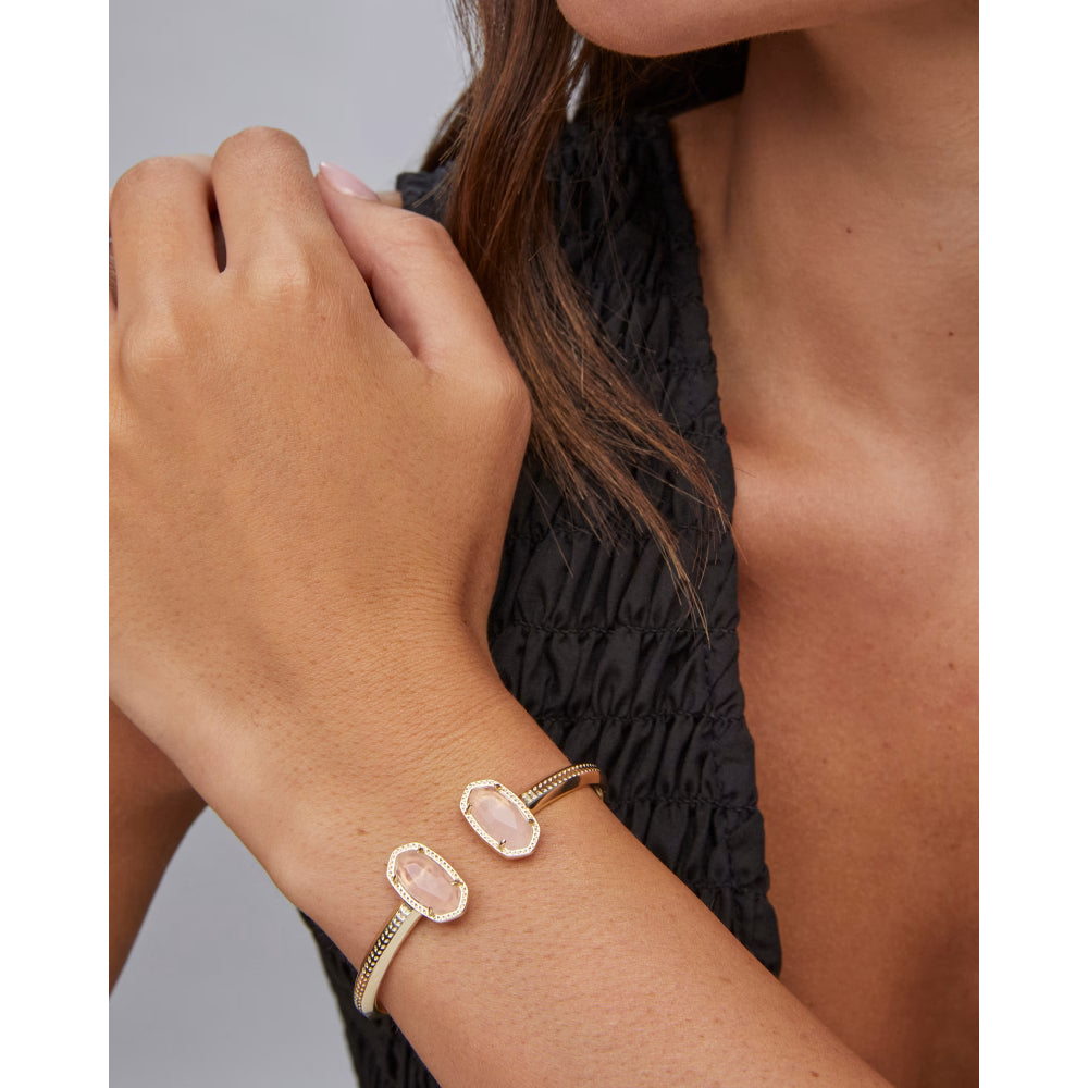 Gold bracelet with a stone on a wrist against a neutral background
