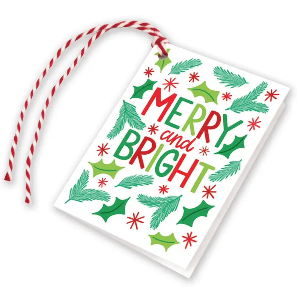 A white Christmas greeting card with a red and white striped hanging ribbon, featuring the words 'MERRY and BRIGHT' in red and green lettering surrounded by holly leaves, pine branches, and red snowflake motifs.