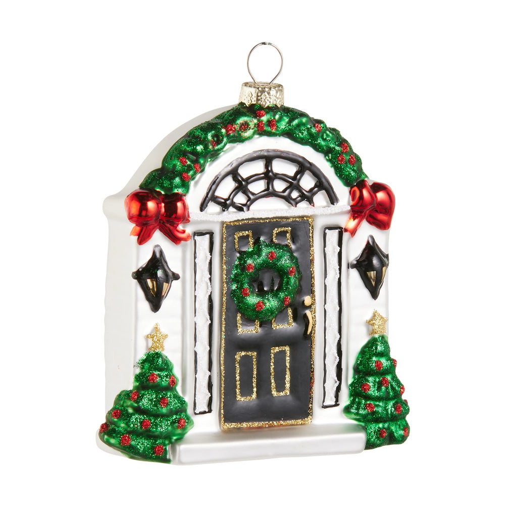 Decorative Christmas ornament of a door with wreath, trees, and bows on a white background.