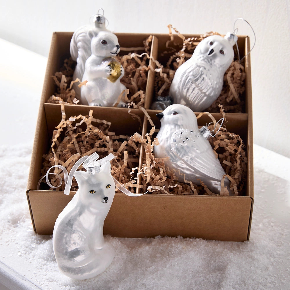 Set of white ceramic animal ornaments in a box with brown tissue paper.