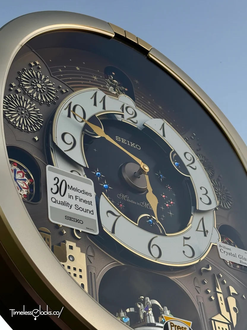 A close-up angled view of a large Seiko wall clock with a dark, ornate design, featuring white clock face rings, gold accents, and a clear outer cover. A white promotional sticker on the left reads '30 Melodies in Finest Quality Sound'.