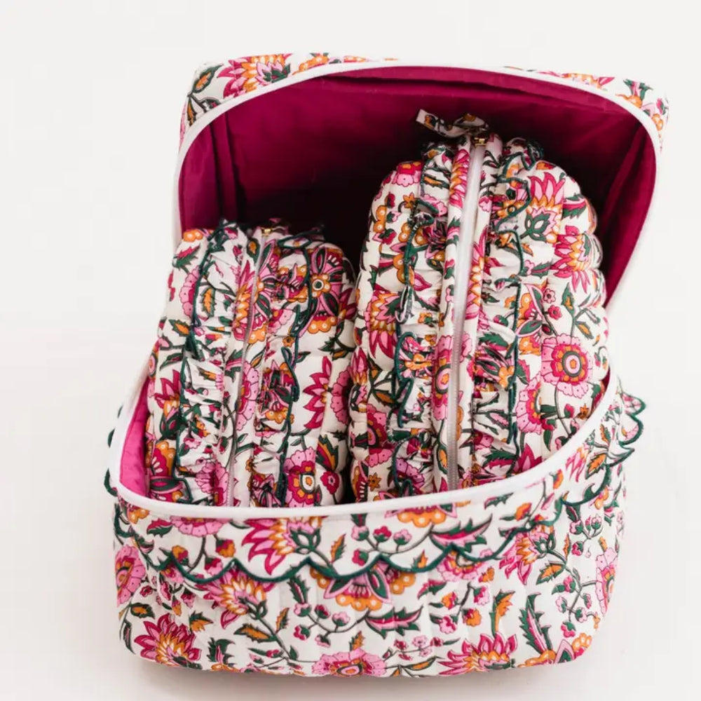 A floral zippered travel organizer bag shown open, containing matching pouches or sleeves with the same pink, orange, green, and white floral print. The interior lining is dark magenta.