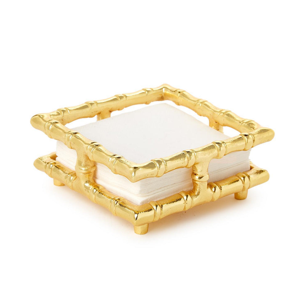 Gold bamboo napkin holder with white napkins on a white backround.