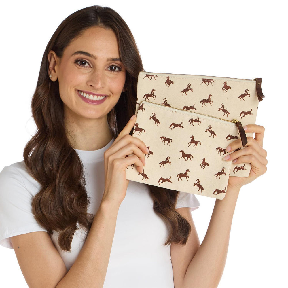 Woman holding a beige large & small pouch with brown horse patterns on a white background.