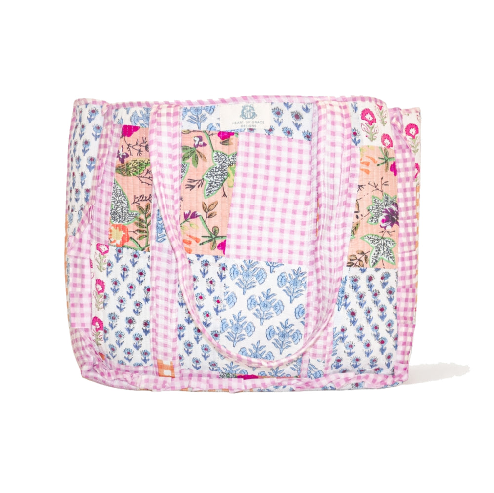 Pink quilted design with floral and checkered patterns on a ruffle tote bag on a white background.
