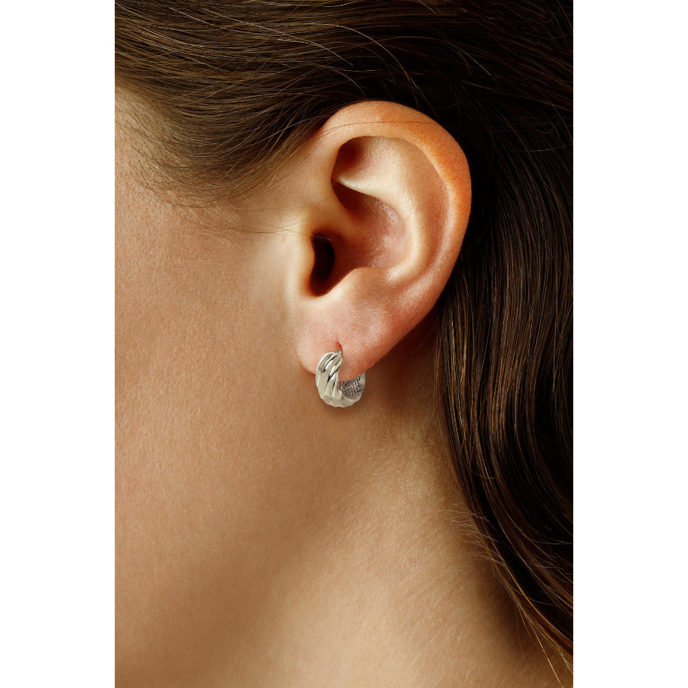 Close-up of an ear wearing a silver earring with dark hair.