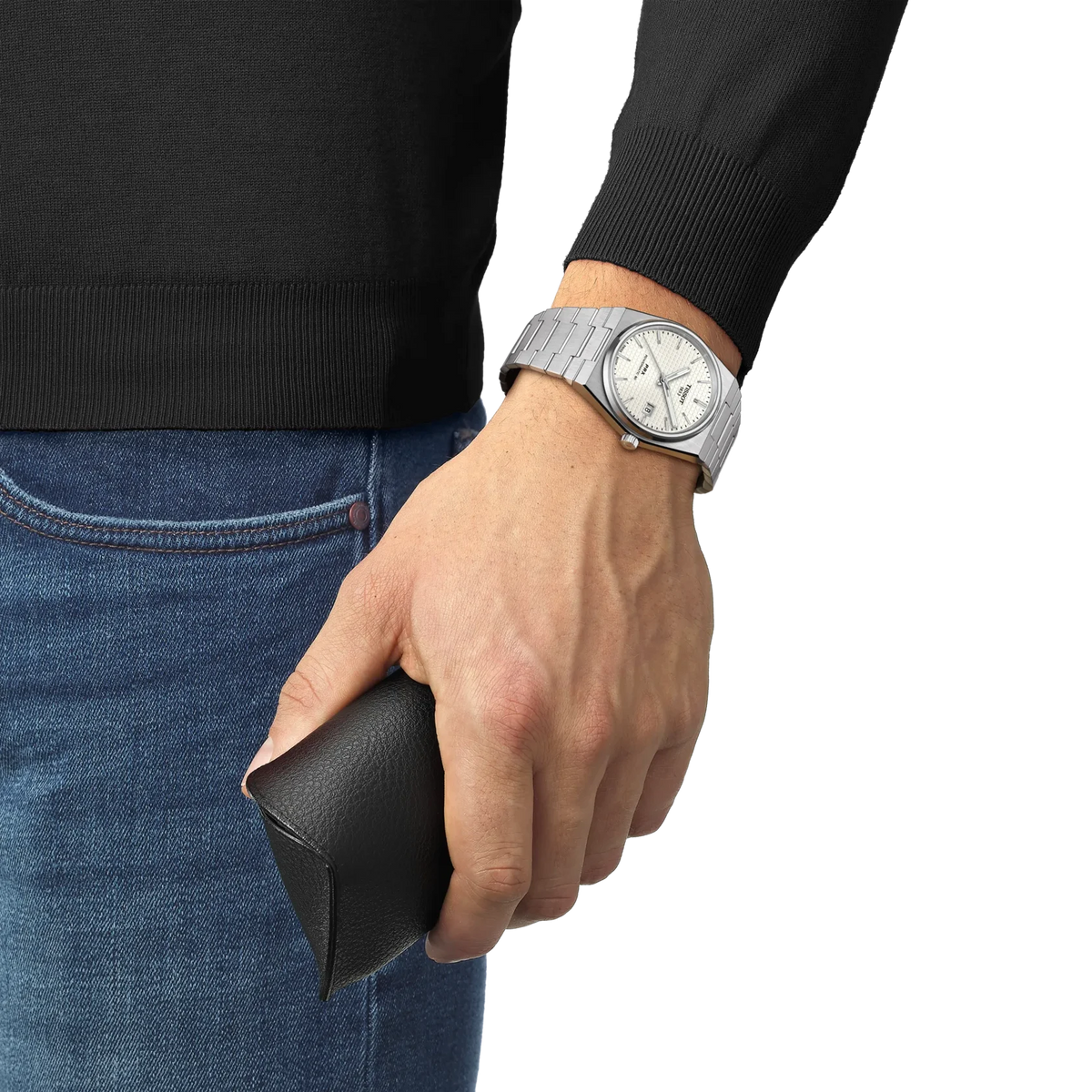 Hand wearing a silver watch holding a black wallet, with a plain background