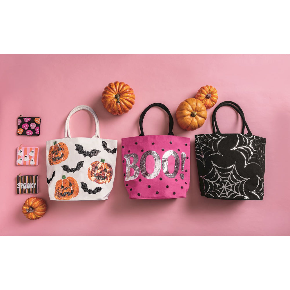 Halloween-themed bags and small pouches and pumpkins on a pink background.