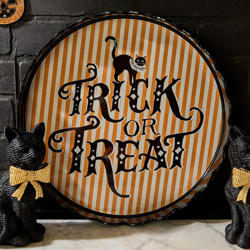 Halloween-themed decorative scalloped edge tray with 'Trick or Treat' text and black cats on a striped background.