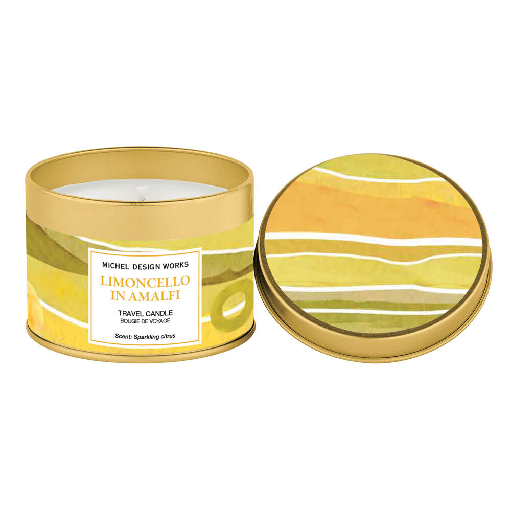 A cylindrical metal candle tin with its lid placed beside it on a white background. The tin and lid feature a yellow, green, and orange abstract wave pattern, with a white label on the front reading 'MICHEL DESIGN WORKS LIMONCELLO IN AMALFI'.