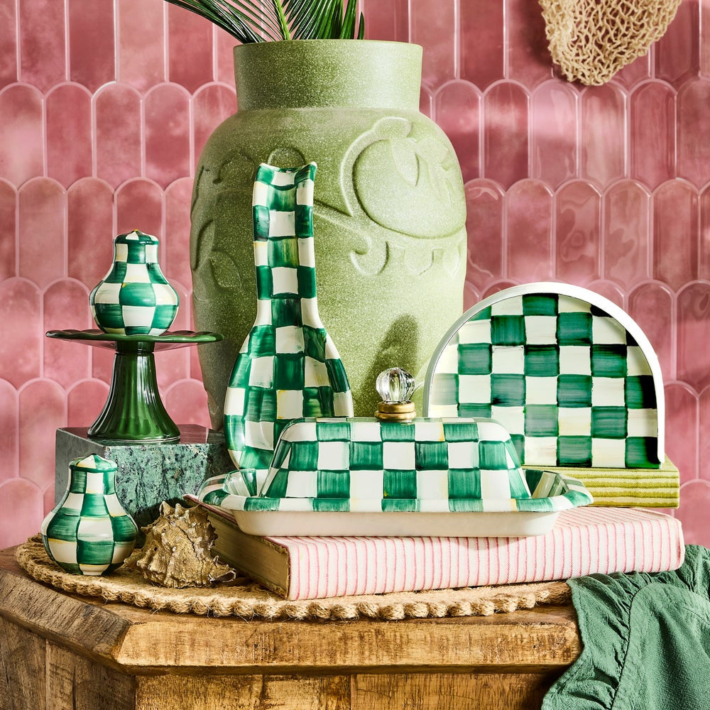 Decorative green and white items on a wooden table with a pink tiled wall background