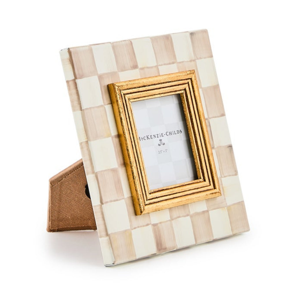 A square Jackson-Childs 2.5x3 picture frame with a checkered pattern in cream and light tan, featuring a gold-toned frame and a small brown fabric backing, shown on a white background.
