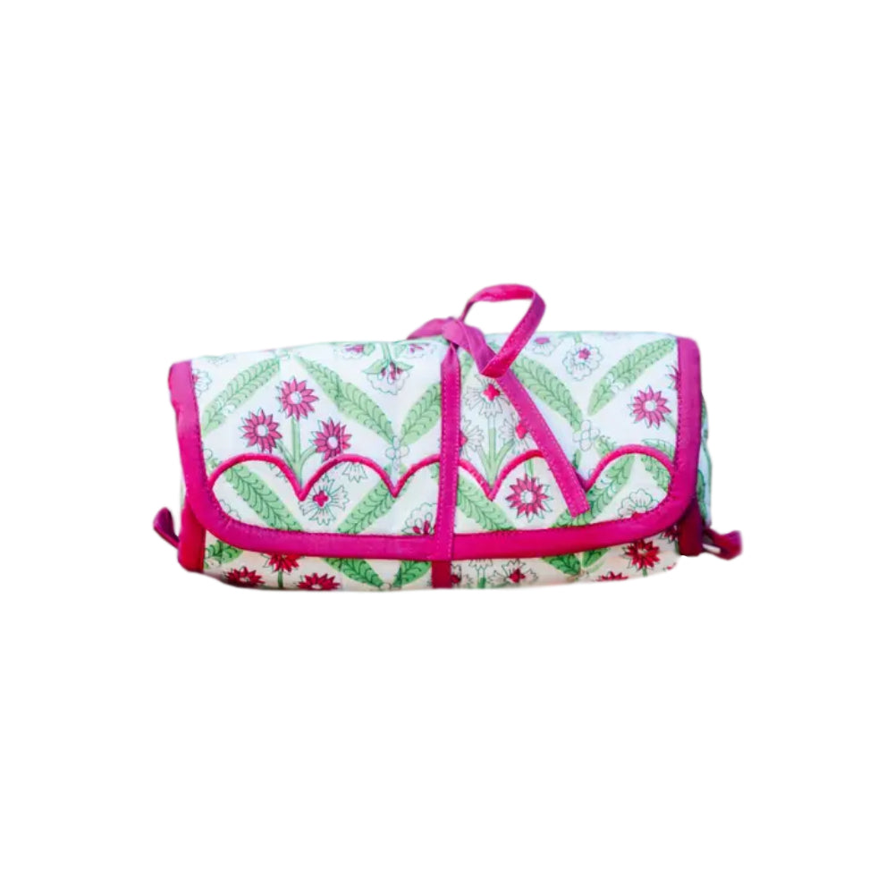 A quilted jewelry roll with a pink and green flower design on a white background