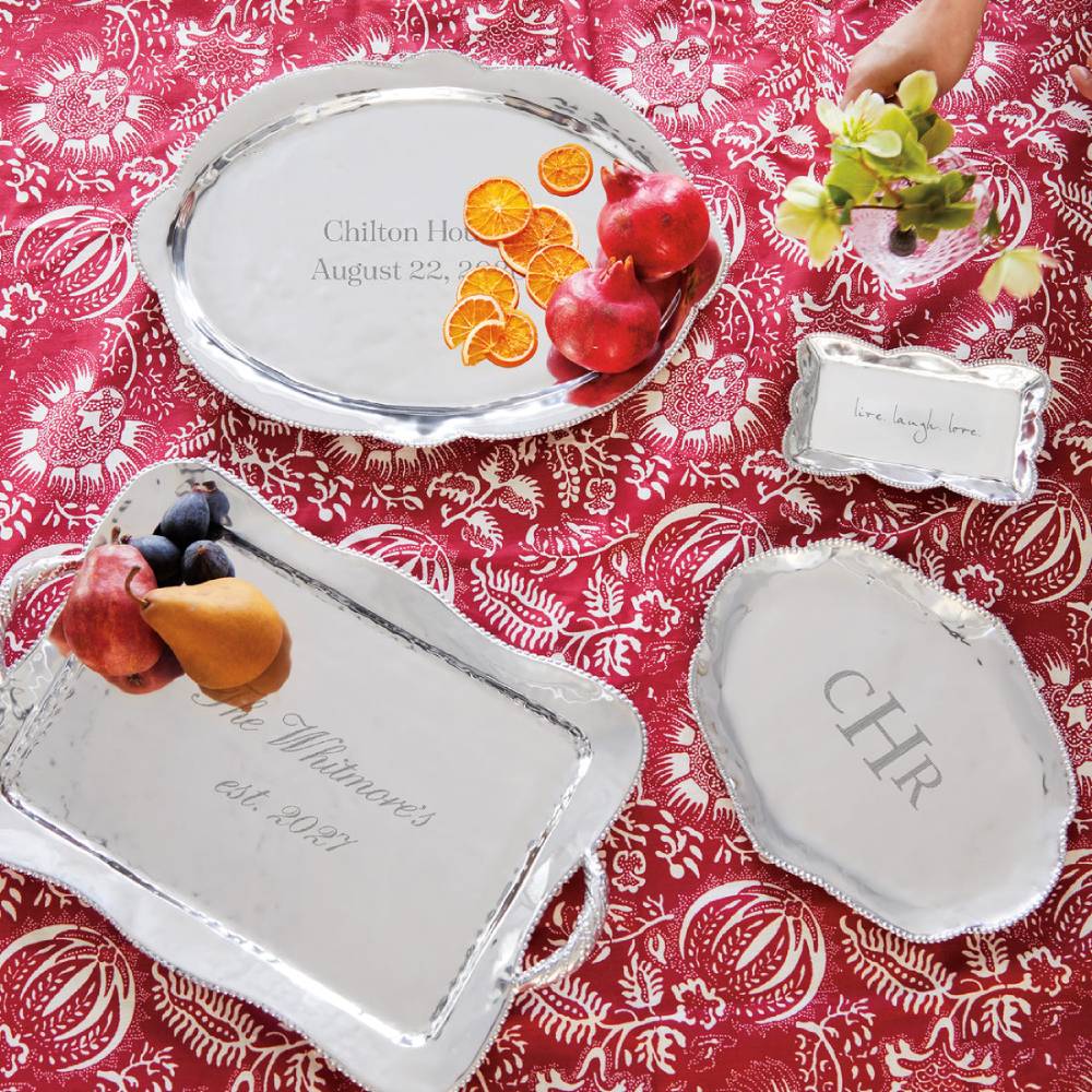Decorative engraved silver trays with fruit on a red patterned tablecloth