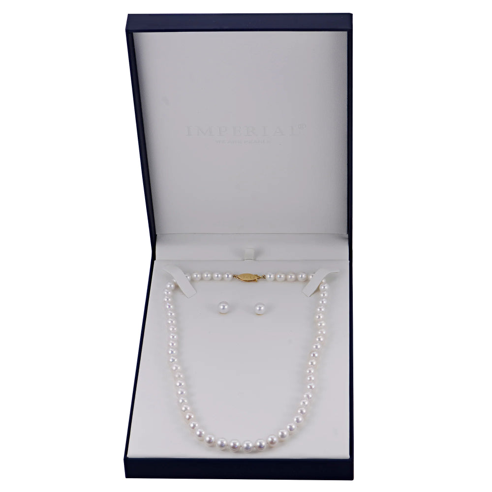 A pearl necklace and matching pearl stud earrings displayed inside an open navy blue jewelry box with a white velvet insert. The inside lid of the box is embossed with the brand name 'IMPERIAL'.