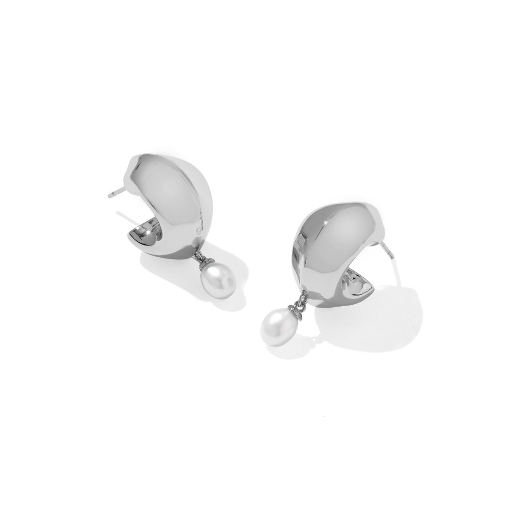A pair of silver huggie hoop earrings with a dangling white pearl, shown on a clean white background with soft shadows.