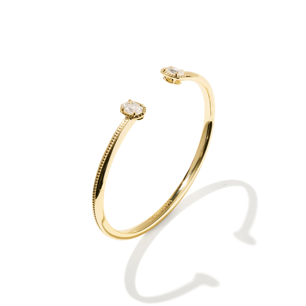 A delicate gold open cuff bracelet with two small round diamond settings, shown on a clean white background with a soft shadow.