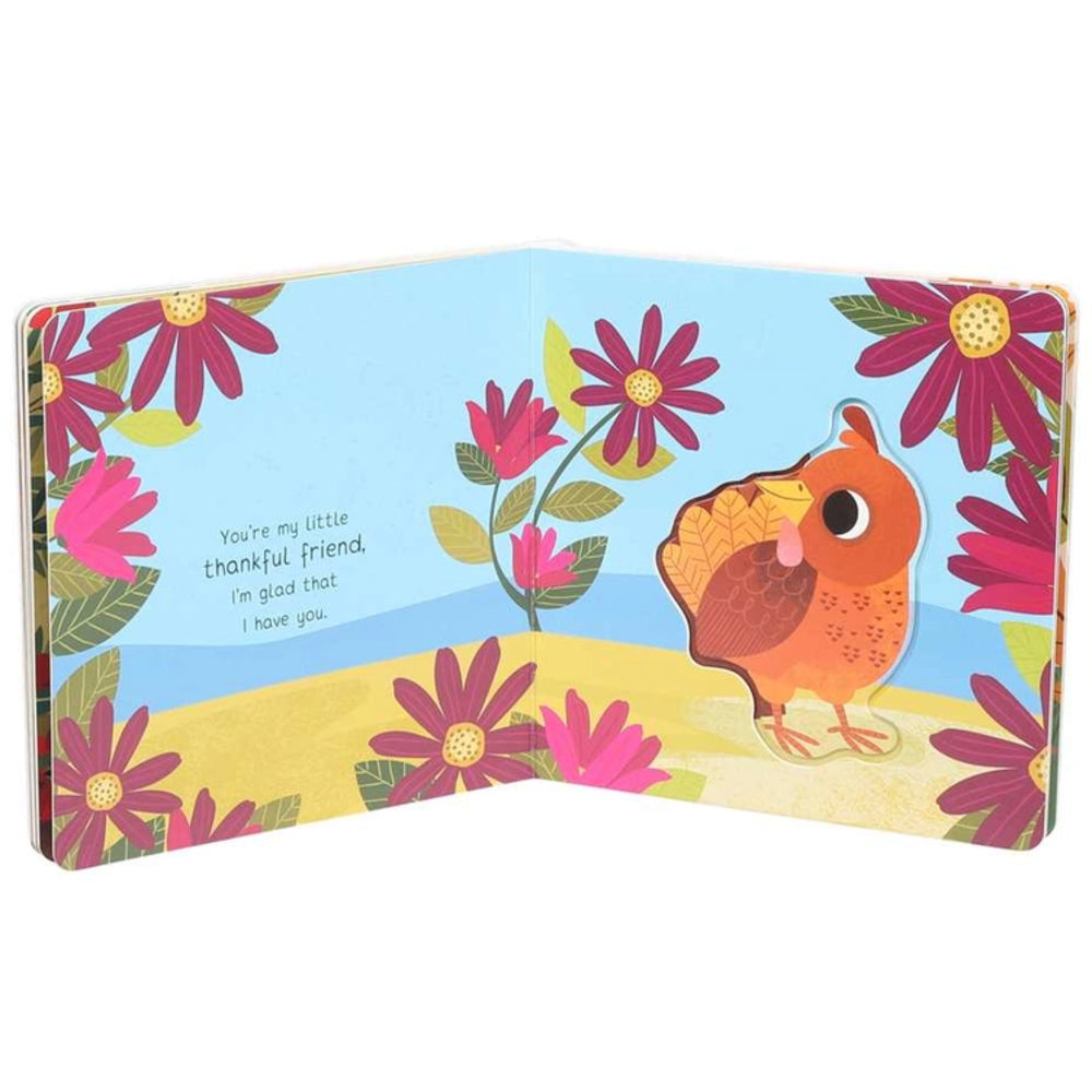 An open children's board book with a colorful illustration of a small brown bird standing on a yellow ground, surrounded by pink flowers on a light blue sky. The left page has the text, 'You're my little thankful friend, I'm glad that I have you.