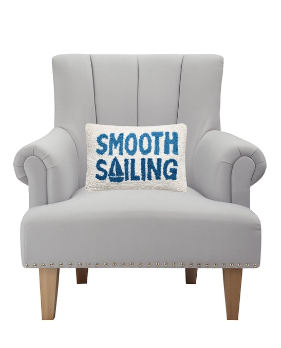 Gray armchair with a pillow that says 'Smooth Sailing' on a white background
