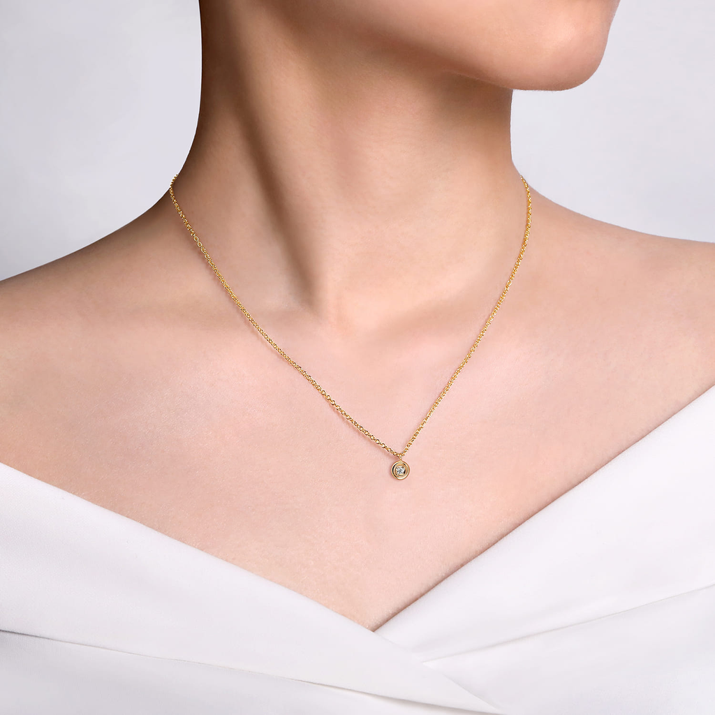 Gold necklace with a small pendant on a white background