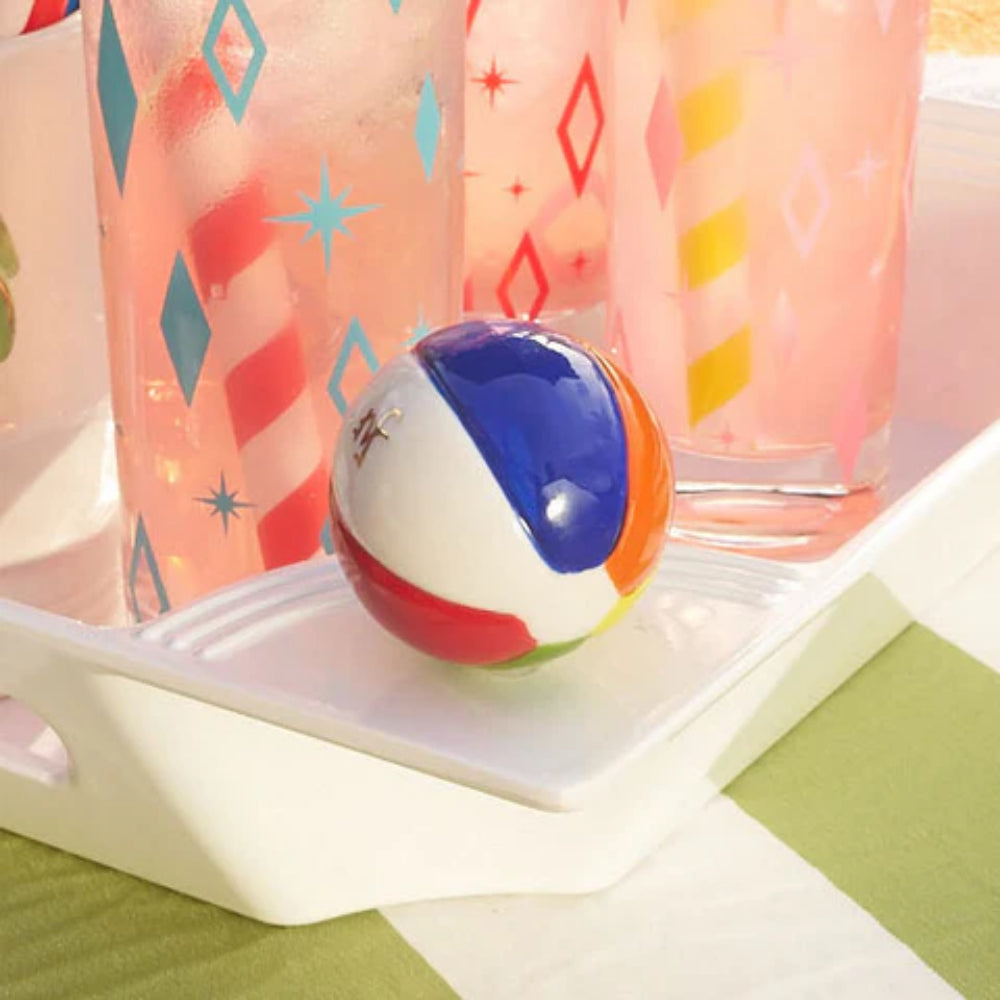 Colorful beach ball on a white tray with patterned glasses in the background.