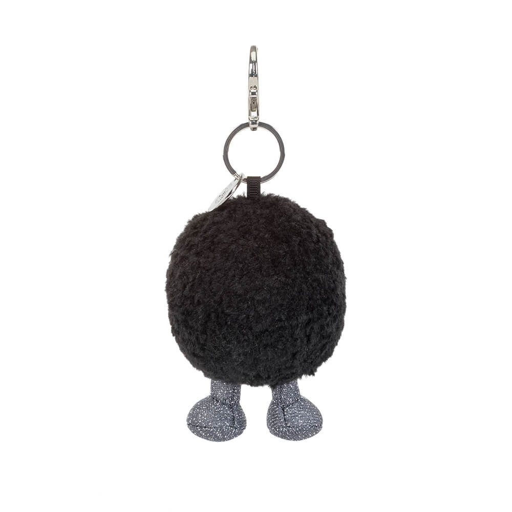 A photo of the back of a black hole plush keychain with a grey and black smiling face and grey legs on a white background.